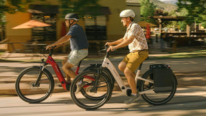 Zwei Personen fahren auf ihren Specialized Como E-Bikes durch eine urbane Gegend